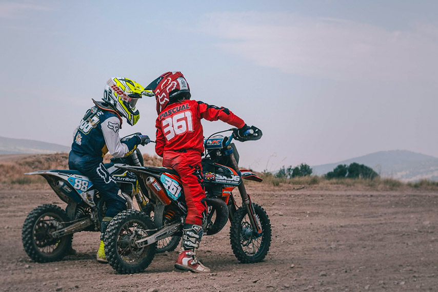 two kids in mini dirt bikes in a motocross circuit